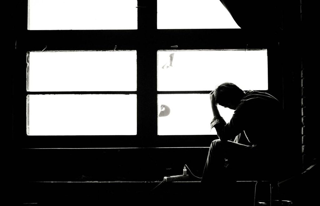 窓際で悩む男性